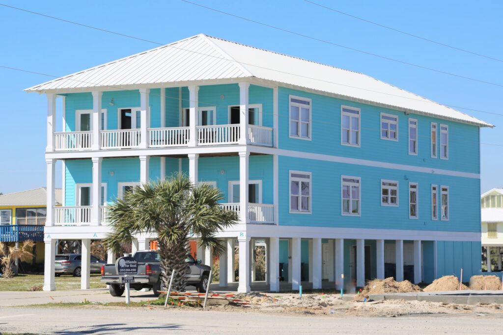 The outside of a 3 bedroom duplex home located in Gulf Shores. The home is blue and located close to the beach