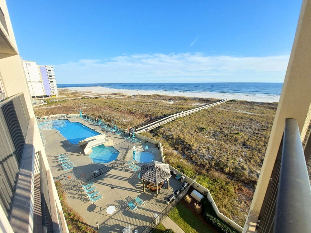 A view of the resort pools and hot tub as well as a distanced view of the beach from the unit Phoenix VII 503 in Orange Beach